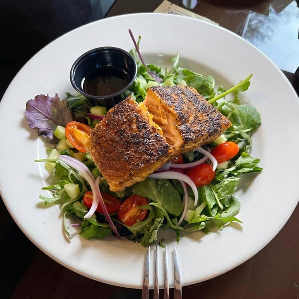 Grilled salmon salad with mixed greens, cherry tomatoes, red onion, and cucumber at Whiskey Kitchen.
